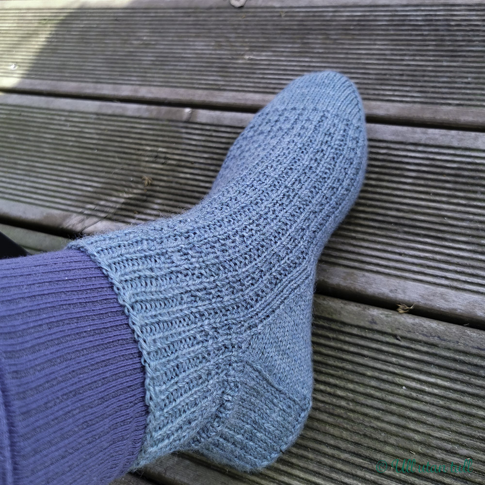 Marianne sin fot med blå lange bomullsokkar og blågrøn strikkasokk
